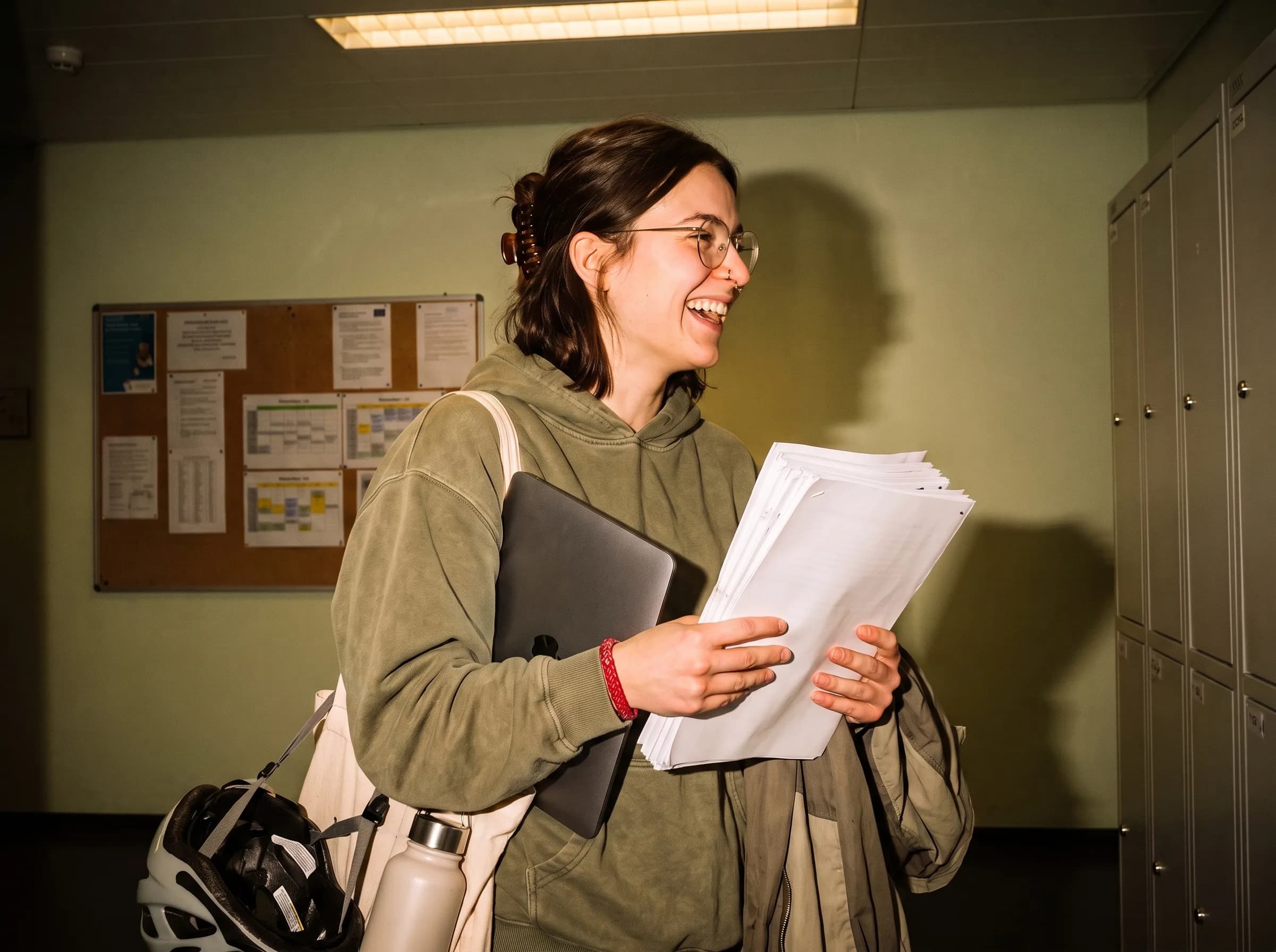 Estudiante sonriendo con su trabajo ya impreso en el pasillo de la universidad